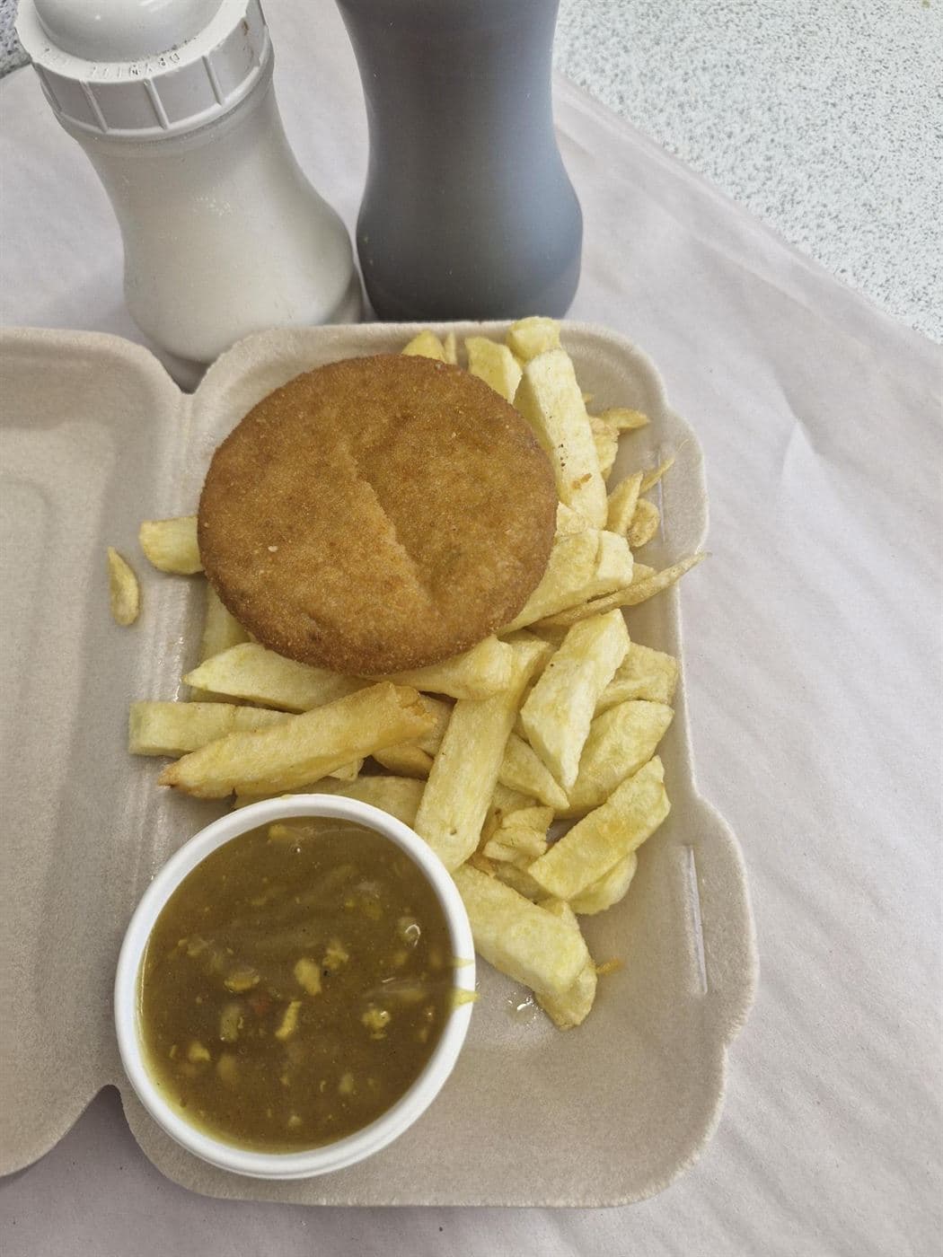 Fishcake with chips and a pot of curry sauce